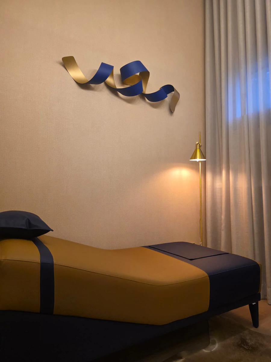 Divã visto de perto, com a luminária dourada acesa ao lado da cortina