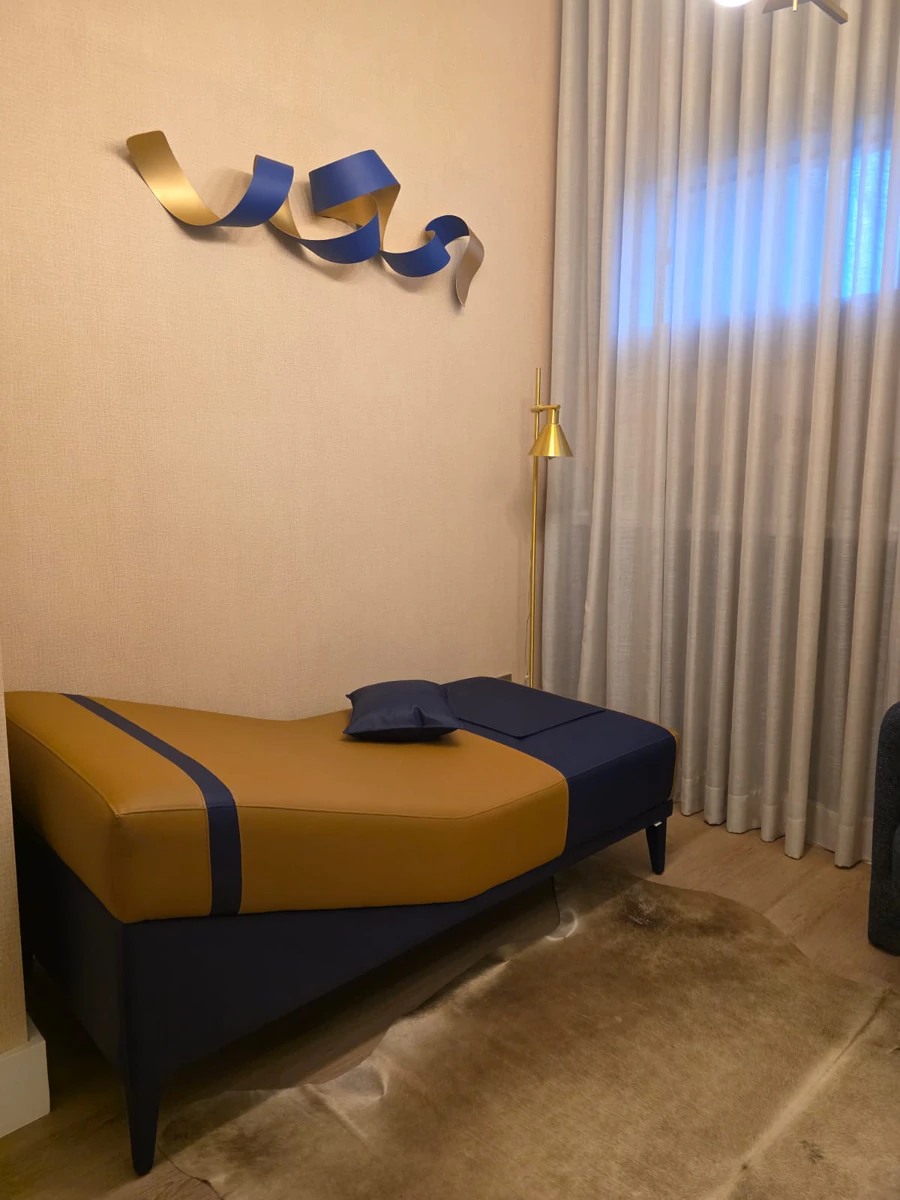Divã do consultório com escultura em fita dourada e azul na parede