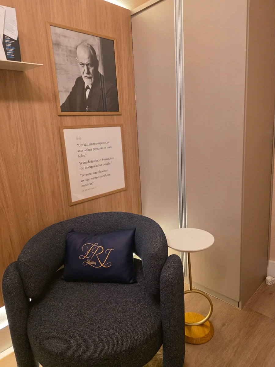Poltrona de atendimento com almofada bordada, mesa lateral e quadro com citação na parede